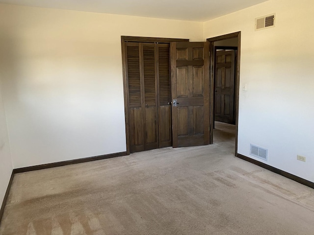 unfurnished bedroom featuring light carpet and a closet