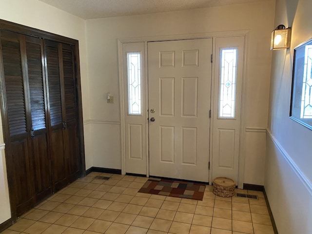 entryway featuring light tile patterned floors, a textured ceiling, and a healthy amount of sunlight