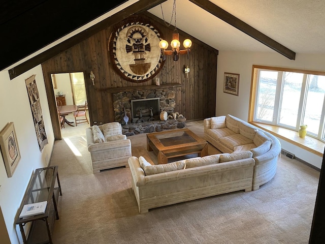 carpeted living room featuring an inviting chandelier, a stone fireplace, wooden walls, vaulted ceiling with beams, and a textured ceiling