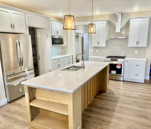 kitchen with appliances with stainless steel finishes, wall chimney exhaust hood, sink, light hardwood / wood-style floors, and white cabinetry