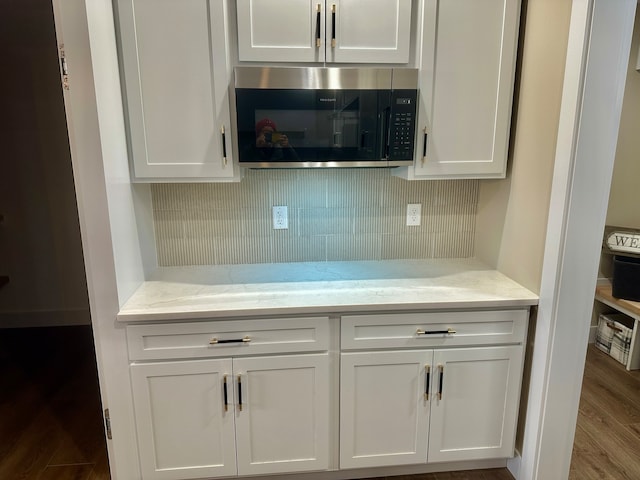 kitchen with light stone countertops, hardwood / wood-style floors, and white cabinets