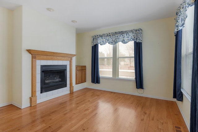 unfurnished living room with hardwood / wood-style flooring and a tile fireplace