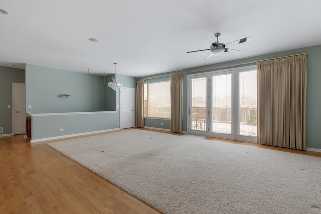 spare room with ceiling fan with notable chandelier and light hardwood / wood-style flooring