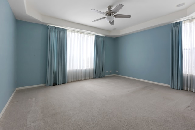 spare room featuring light carpet, a raised ceiling, and ceiling fan