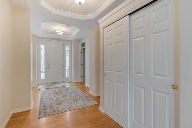 entrance foyer with a raised ceiling, light hardwood / wood-style floors, and ornamental molding