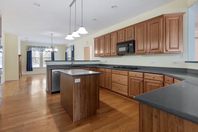 kitchen with light wood-type flooring, black appliances, decorative light fixtures, a notable chandelier, and a center island