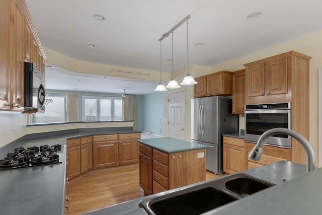 kitchen with stainless steel appliances, ceiling fan, pendant lighting, light hardwood / wood-style flooring, and a kitchen island