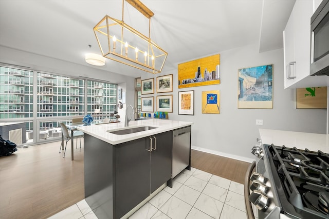 kitchen featuring sink, stainless steel appliances, an inviting chandelier, decorative light fixtures, and light wood-type flooring