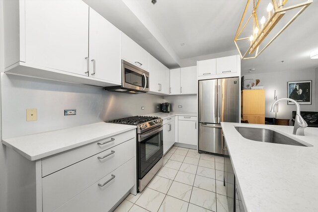 kitchen featuring hanging light fixtures, white cabinetry, sink, and appliances with stainless steel finishes