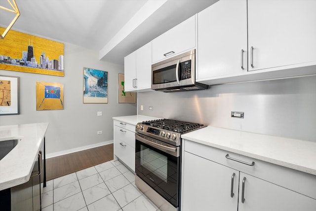 kitchen with white cabinets, stainless steel appliances, and light hardwood / wood-style floors