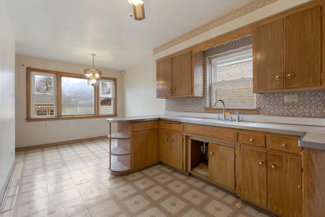 kitchen with decorative light fixtures, decorative backsplash, sink, and kitchen peninsula