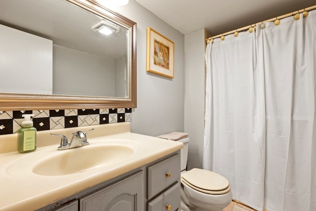 bathroom with vanity, toilet, and tasteful backsplash