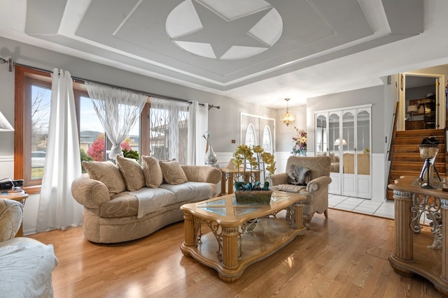 living room featuring a chandelier, a tray ceiling, and light hardwood / wood-style floors