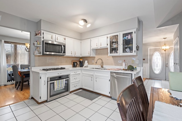 kitchen featuring an inviting chandelier, sink, appliances with stainless steel finishes, decorative light fixtures, and white cabinetry