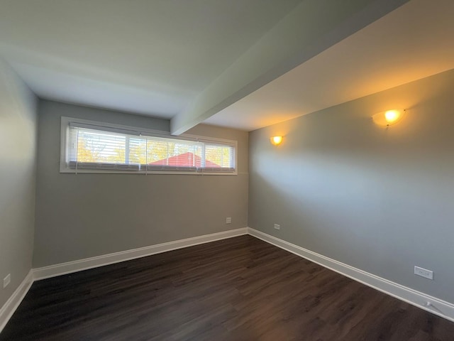 empty room featuring beamed ceiling and dark hardwood / wood-style floors