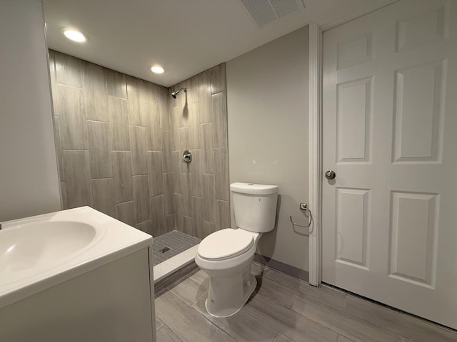 bathroom featuring vanity, toilet, and tiled shower