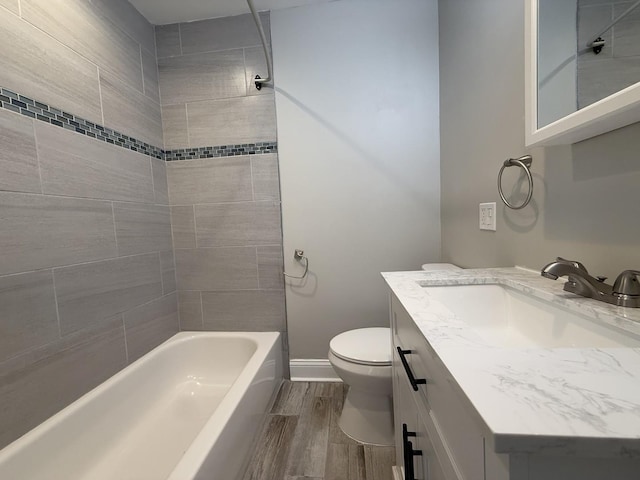 full bathroom featuring vanity, hardwood / wood-style floors, tiled shower / bath, and toilet