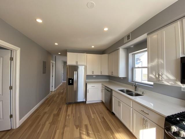 kitchen featuring white cabinets, sink, light wood-type flooring, and stainless steel appliances