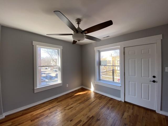 interior space with a wealth of natural light, ceiling fan, and dark hardwood / wood-style floors