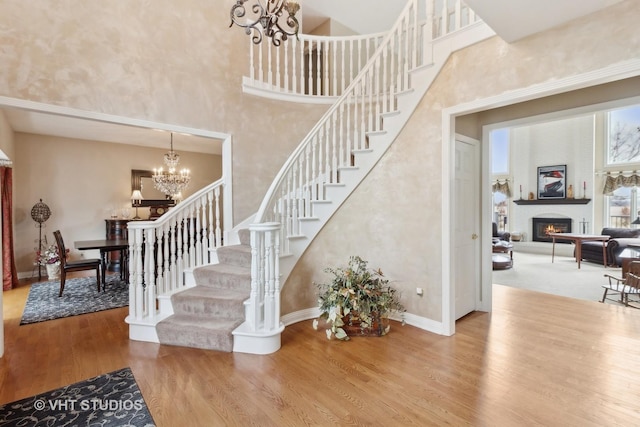 stairs with a notable chandelier, hardwood / wood-style flooring, and a high ceiling