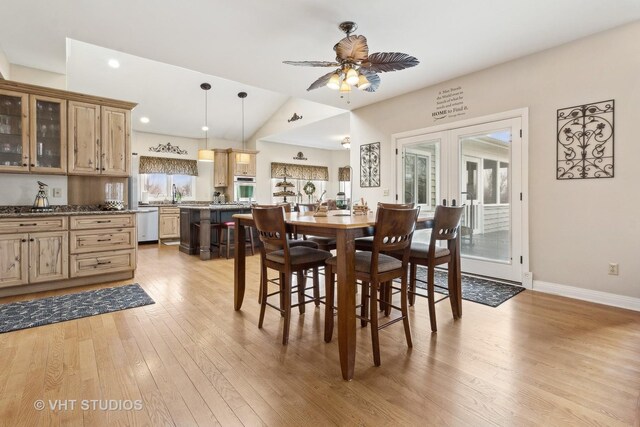 dining space featuring sink, light hardwood / wood-style flooring, ceiling fan, vaulted ceiling, and french doors