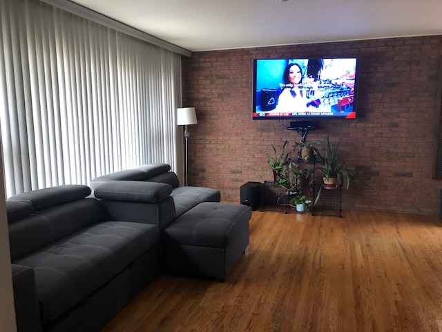 living room featuring hardwood / wood-style flooring and brick wall