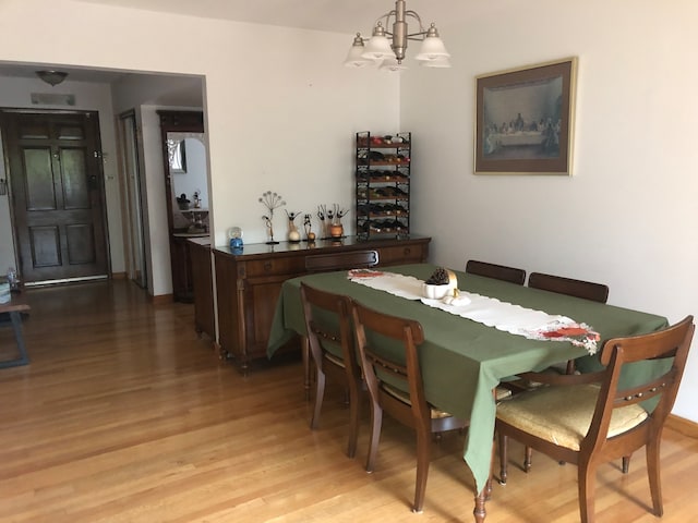 dining space with light hardwood / wood-style floors and an inviting chandelier