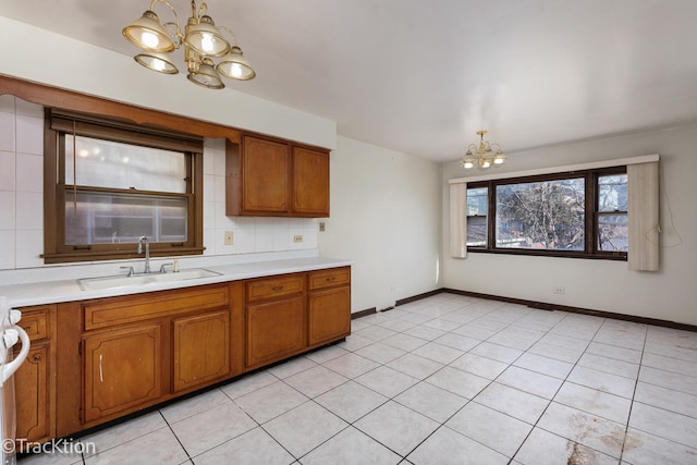 kitchen featuring sink, light tile patterned floors, an inviting chandelier, backsplash, and hanging light fixtures