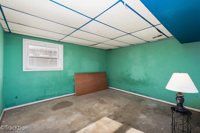 unfurnished room with a paneled ceiling and concrete flooring