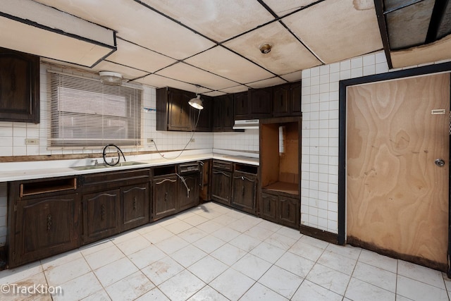 kitchen featuring tasteful backsplash, dark brown cabinetry, light tile patterned flooring, and sink