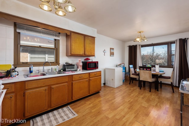 kitchen featuring tasteful backsplash, sink, a chandelier, hanging light fixtures, and light hardwood / wood-style floors