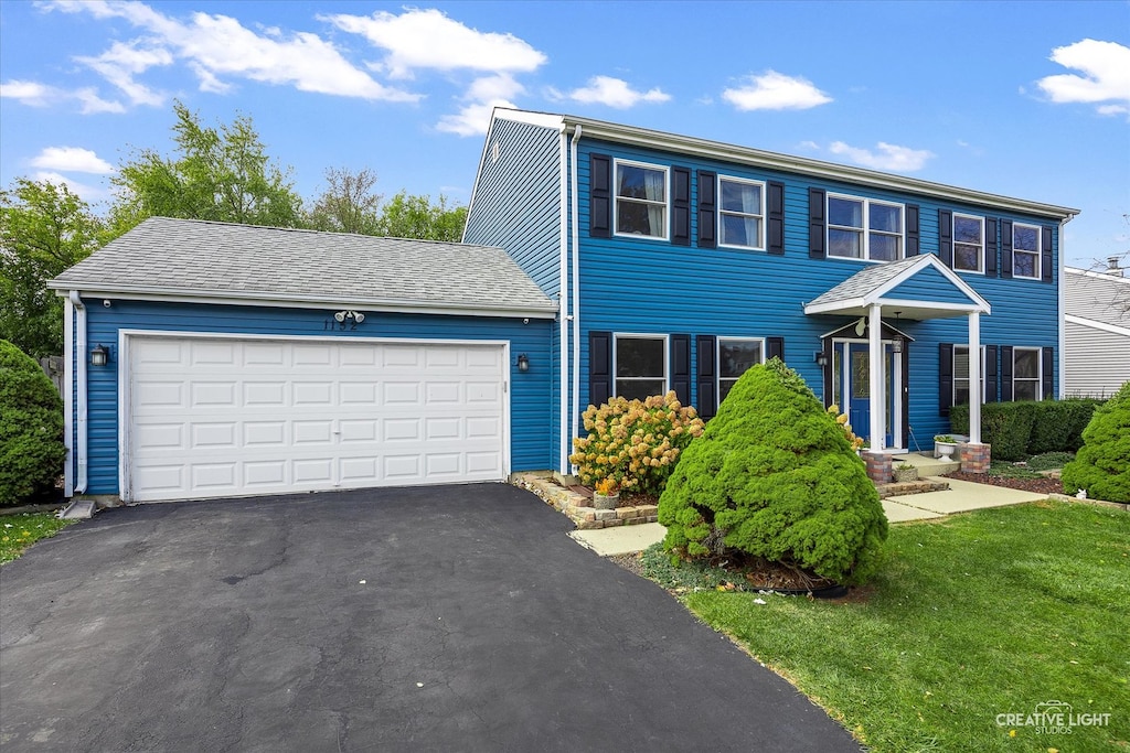 colonial home with a garage and a front lawn