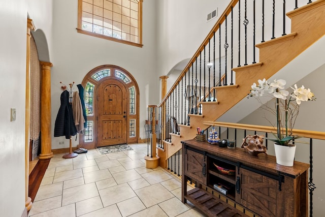 tiled foyer with decorative columns and a high ceiling