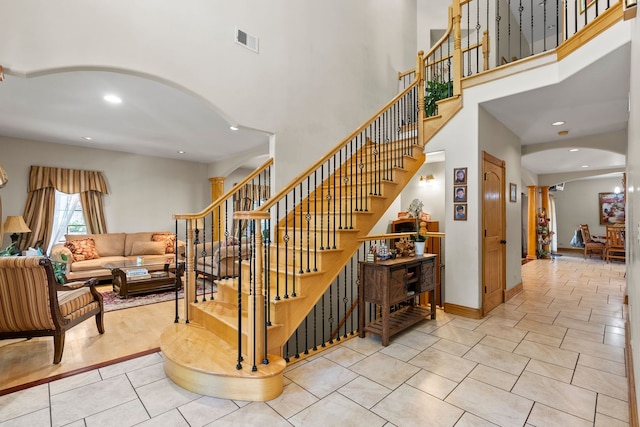 stairway with tile patterned flooring, a high ceiling, and ornate columns