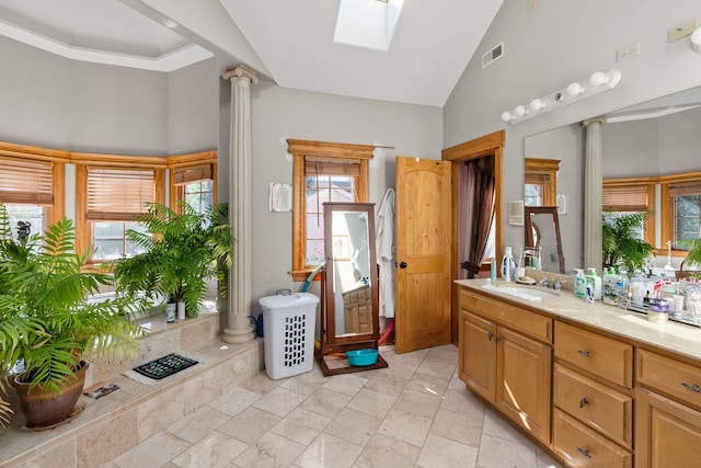 bathroom with vanity, ornate columns, high vaulted ceiling, and a skylight