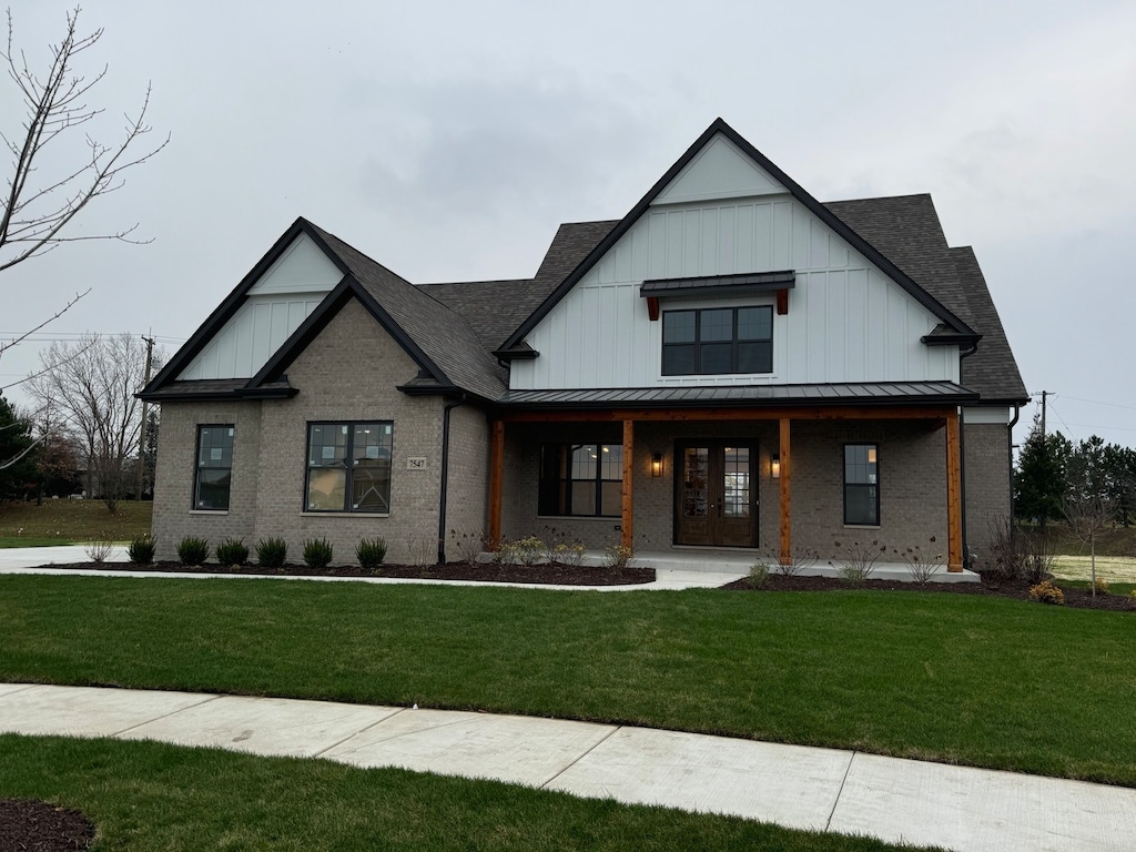 modern farmhouse style home featuring covered porch and a front yard