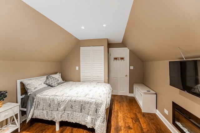 bedroom featuring vaulted ceiling, dark wood-type flooring, and a closet