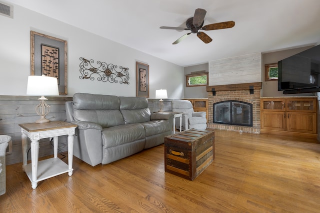 living room with ceiling fan, light hardwood / wood-style floors, and a brick fireplace