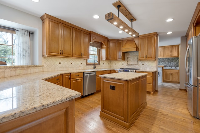 kitchen featuring a kitchen island, light hardwood / wood-style floors, stainless steel appliances, and a wealth of natural light