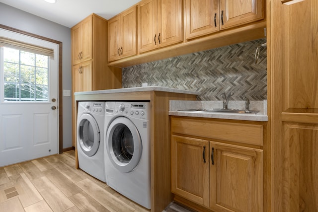 laundry room featuring washer and dryer, light wood-type flooring, cabinets, and sink