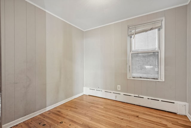 empty room with ornamental molding, a baseboard radiator, and wood-type flooring