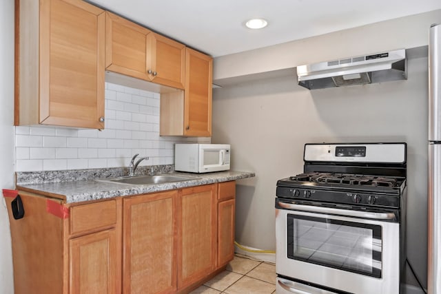 kitchen featuring decorative backsplash, sink, light tile patterned floors, stainless steel range with gas cooktop, and range hood