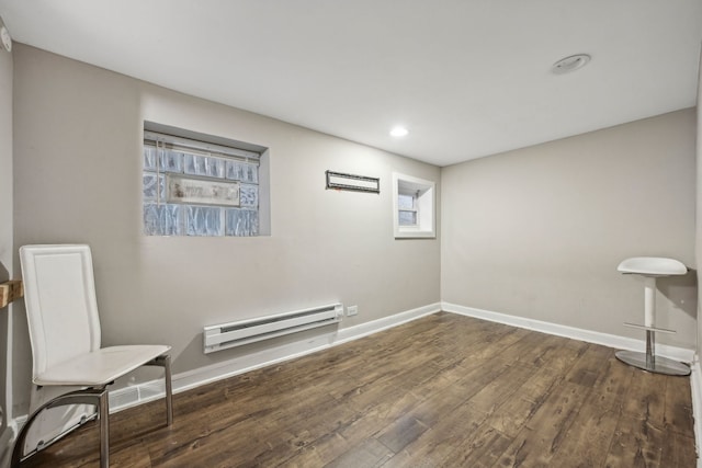 unfurnished room with dark wood-type flooring and a baseboard heating unit