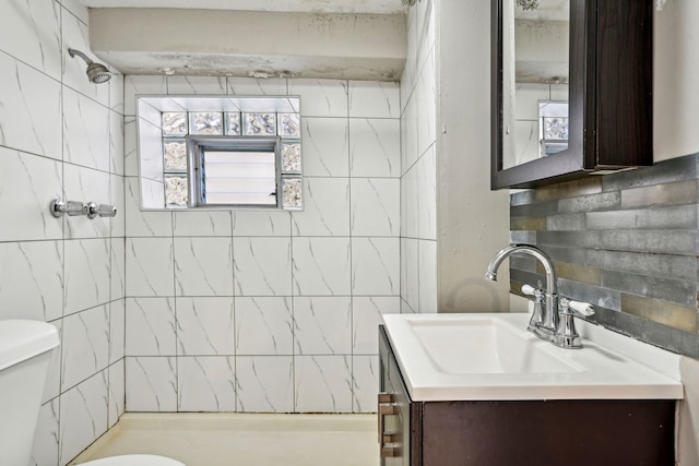 bathroom with a tile shower, vanity, tasteful backsplash, and toilet