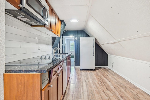 kitchen featuring light wood-type flooring, tasteful backsplash, sink, white fridge, and lofted ceiling