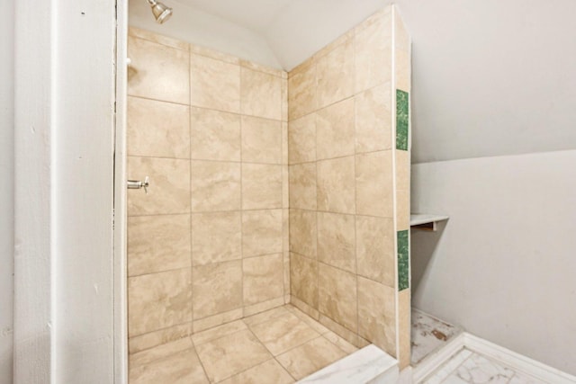 bathroom featuring a tile shower and lofted ceiling