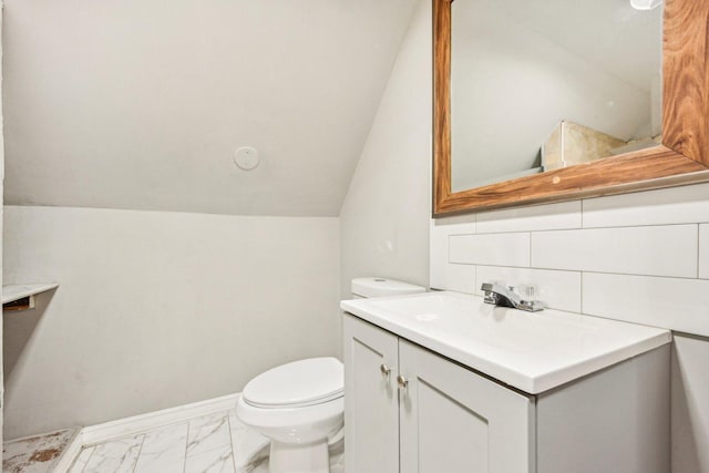 bathroom featuring vanity, toilet, lofted ceiling, and backsplash