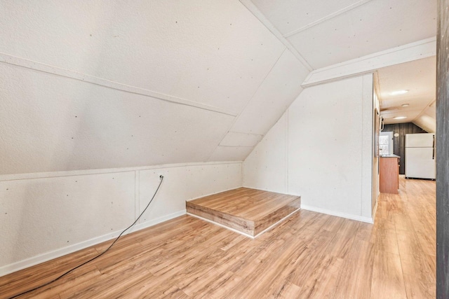 additional living space with light hardwood / wood-style flooring and vaulted ceiling