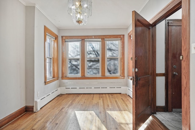 doorway to outside featuring light hardwood / wood-style floors, baseboard heating, crown molding, and an inviting chandelier