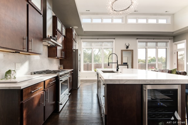 kitchen with a center island with sink, sink, plenty of natural light, stainless steel appliances, and beverage cooler